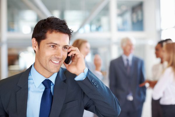 Geschäftsmann steht in einem Foyer und telefoniert mit dem Handy.